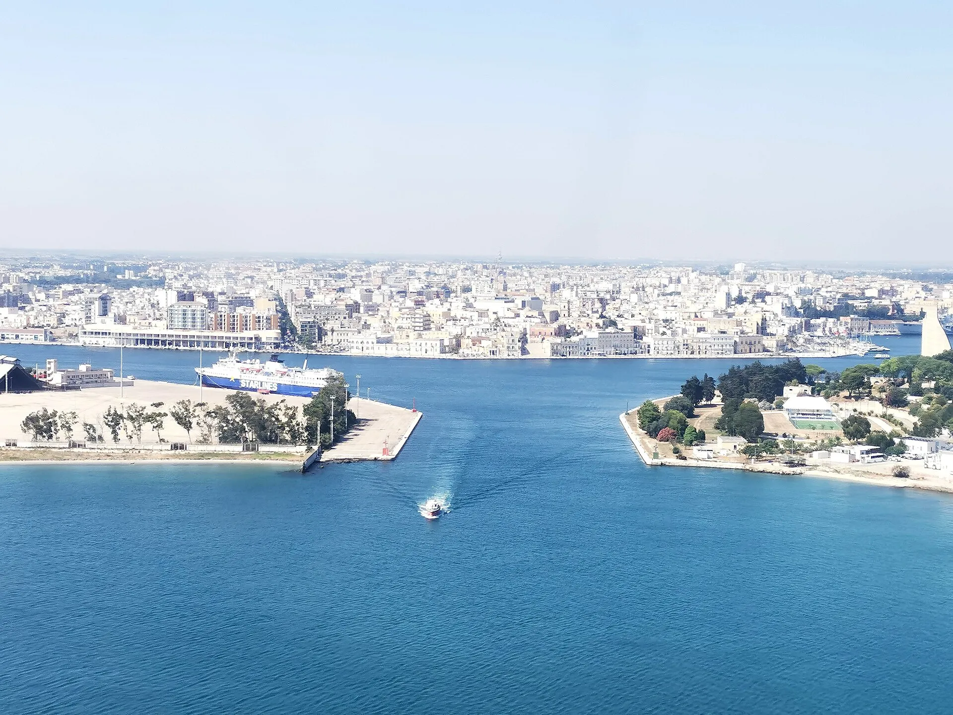 Modern Brindisi waterfront with boats and palm trees, photographed in 2024